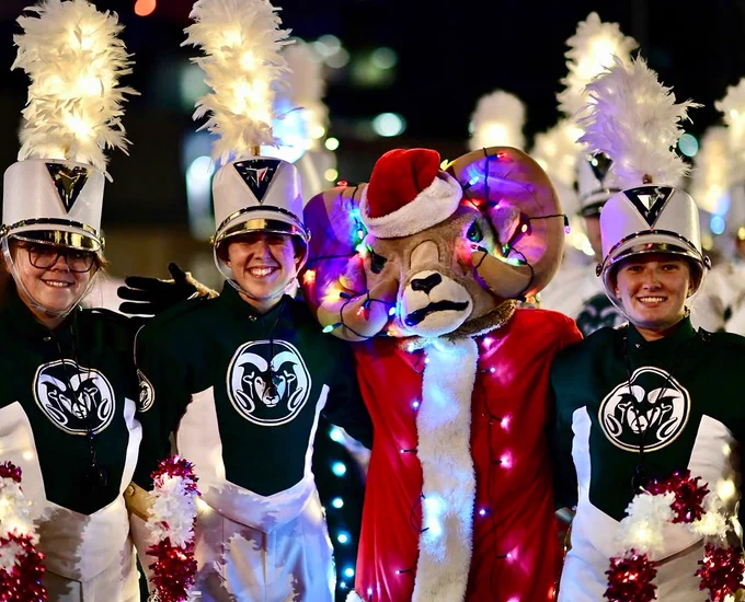 Cam the Ram the mascot posing for a picture with two members of the C S U Marching Band.