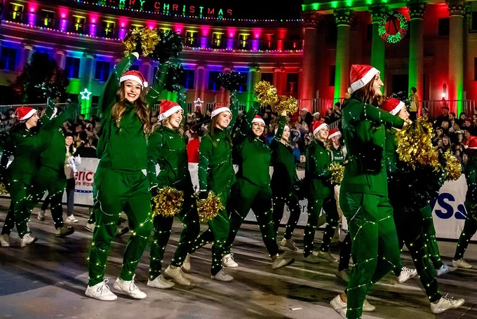 C S U cheer and Golden Poms members waving their pom poms while walking in the 9 News Parade of Lights.