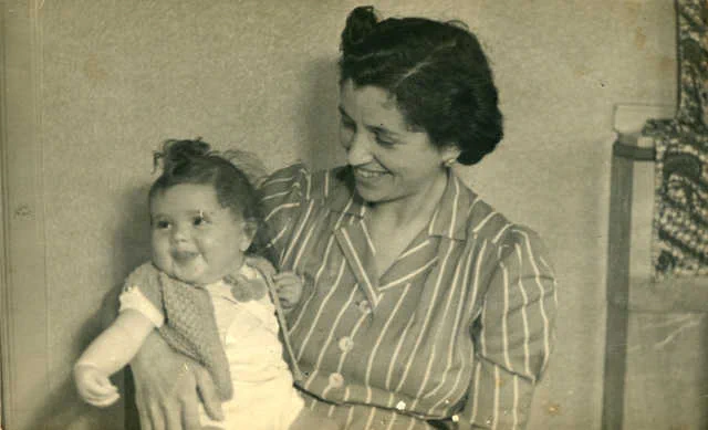 Vintage black and white photograph of a woman holding a smiling baby, both appearing joyful.