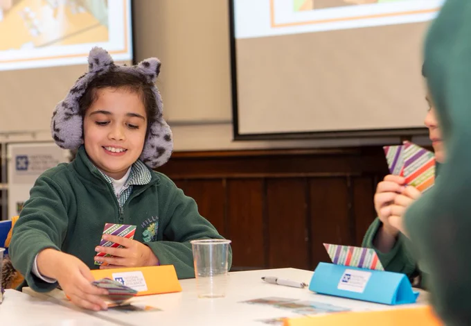 Image shows a young person playing the card game with a set of cards in hand. 
