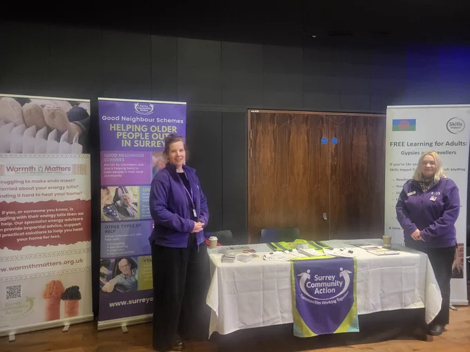 Jo and Vicki stand next to a table  which has leaflets on. There are pop up banners behind them.
