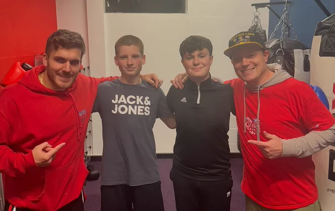 Dan Powell in a red jumper looking at the camera alongside three other men