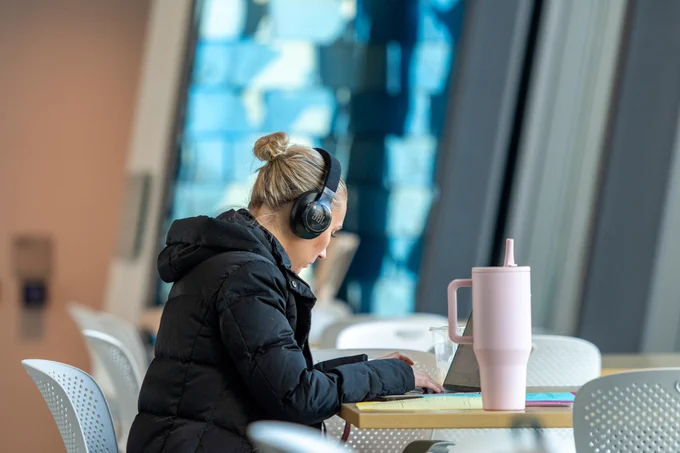A Boise State student studying with headphones on in the Center for the Visual Arts.