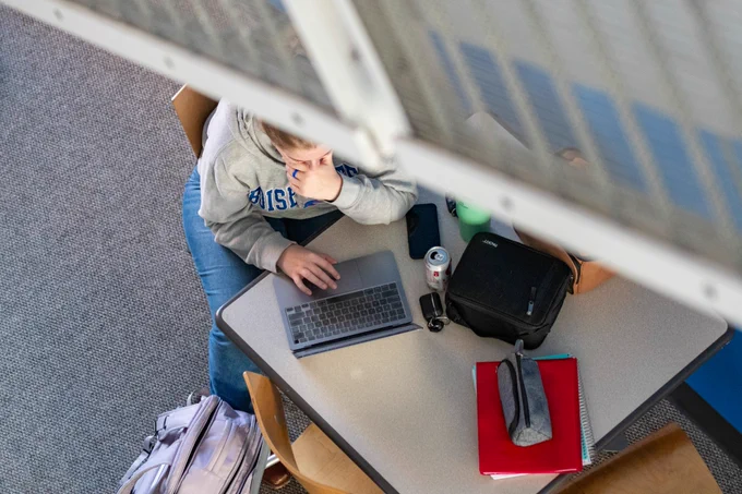 An overhead view of a student working at a table under a stairwell.