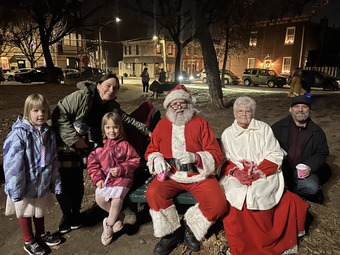 Santa and Mrs. Claus smile with a happy family in Konrad Square during the Winter Holiday Singalong