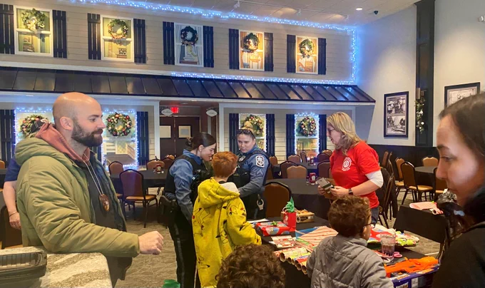 A Deputy U.S. Marshal escorts local children to the table to wrap Christmas gifts.