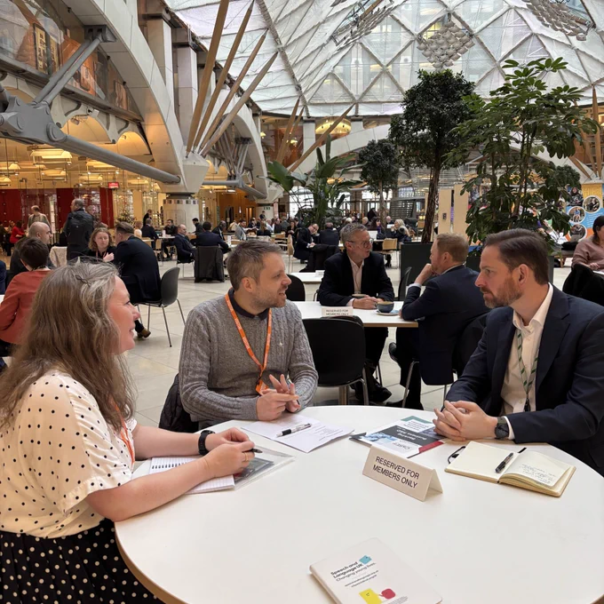 Photo of Alex and Daniel and Becky sat a table talking