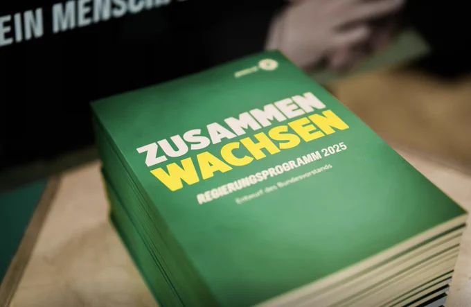 Stapel an Wahlprogrammen der Grünen, auf denen steht: Zusammen Wachsen.