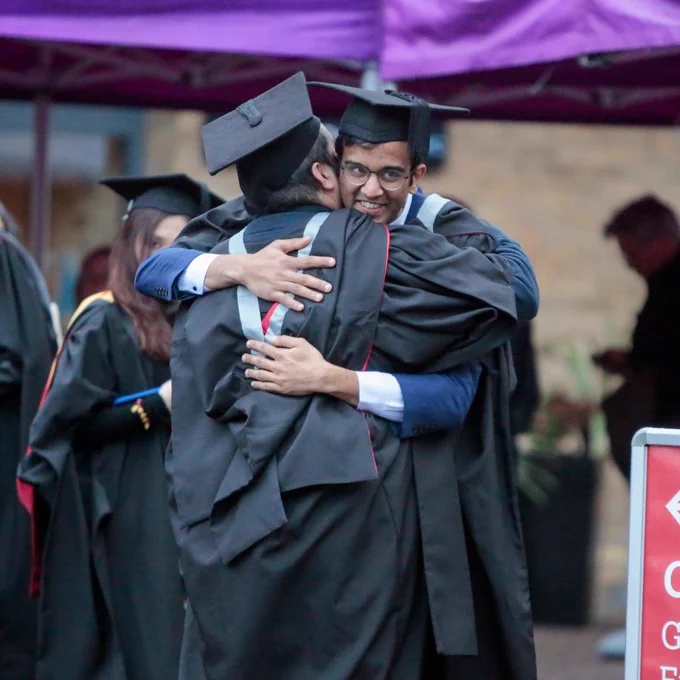 Two graduating students hugging each other.