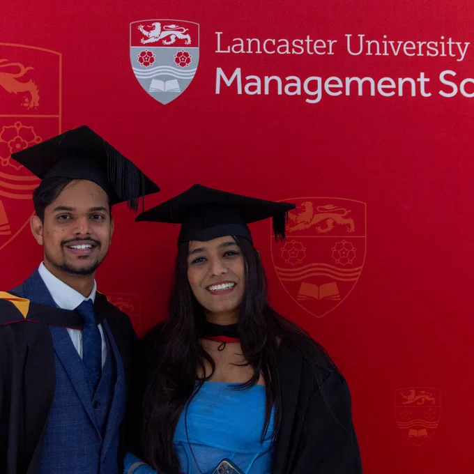 Two graduating students and looking towards camera.