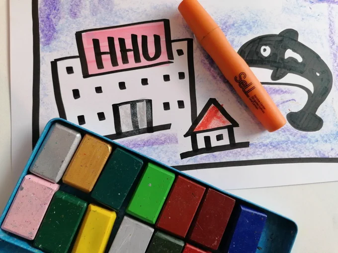 Ein buntes Kunstwerk mit Pastellkreiden, einem orangefarbenen Marker und Illustrationen von Gebäuden und einem Orca. 