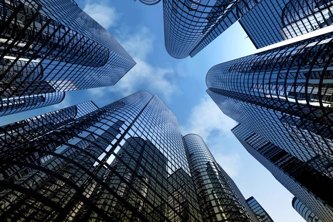 An upward-facing photograph of skyscrapers and a blue sky.