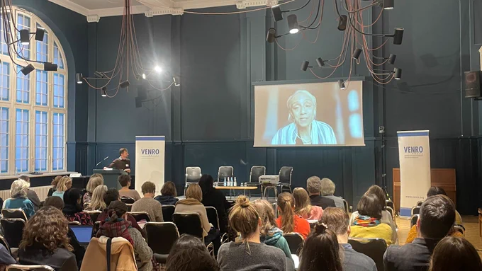 Das Bild zeigt Kavita Ramdas auf einer Leinwand während ihrer Rede.