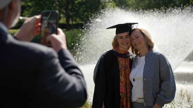 Mother and daughter (graduate) getting their photo taken outside of the Sir Dennis Rooke Fountain.