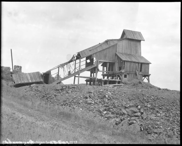 Abandoned and crumbling mine shaft house atop a poor-rock pile