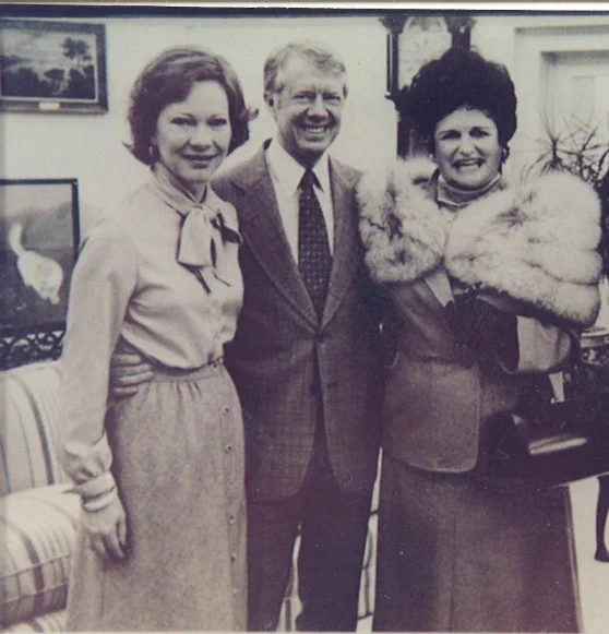 A black and white photo of Powers (at left) with her cousin former President Jimmy Carter and the late Rosalynn Carter. 