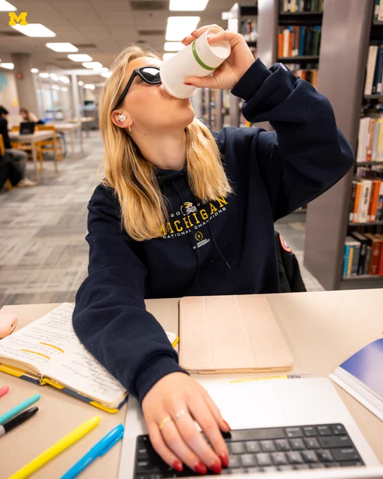 A U-M student drinks coffee while studying in Shapiro Library.