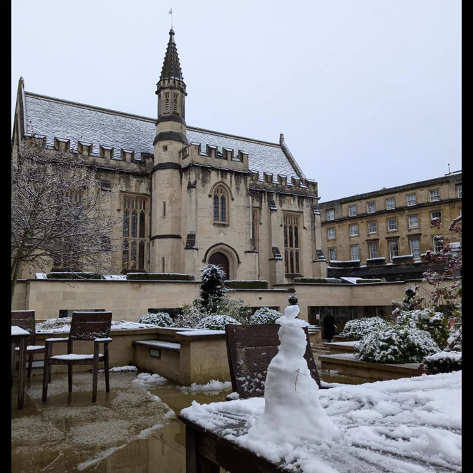  
Photograph of the Longwall Library, on a snowy day, its roof covered with a light dusting of snow. In the foreground, a small snowman has been built on one of the tables in the library courtyard.
