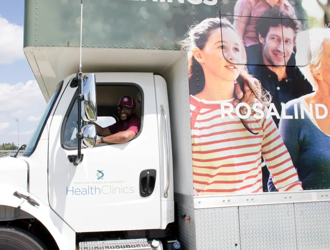 A sideview of an RFU driver smiling while behind the Community Care Coach.
