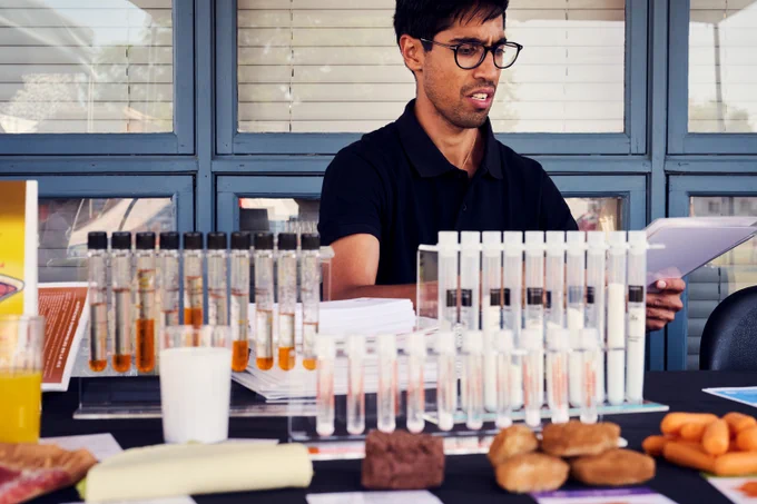 Community member sitting behind a table with various capsules and foods. 