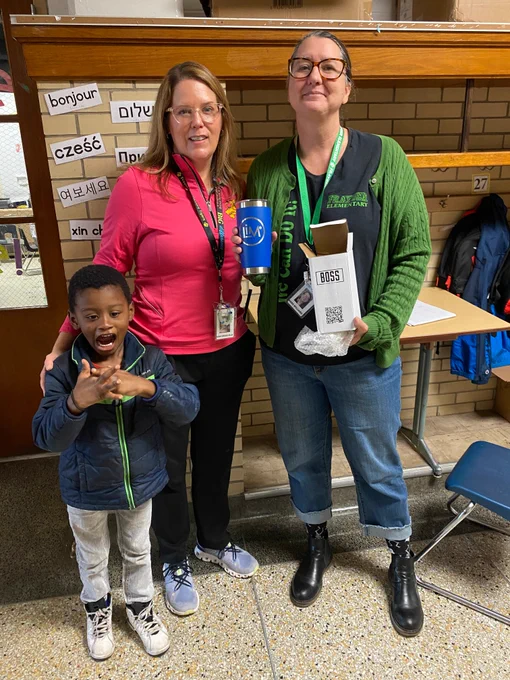 Three people pose for a picture. One holds a mug.