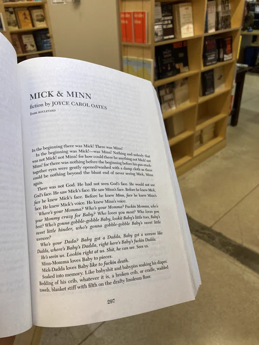 The first page of Joyce Carol Oates' "Mick & Minn," held out in front of some bookshelves. 