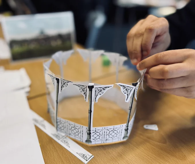 Photo of a young person sticking decorative paper parts onto a bandstand model.