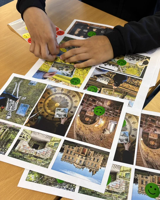 Photo of A4 sheets of paper on a desk. The paper has coloured photos printed onto them. The photos show places and activities undertaken by the pupils. Green smiley face stickers have been placed on some of the photos. A young person’s hands are adding another sticker.