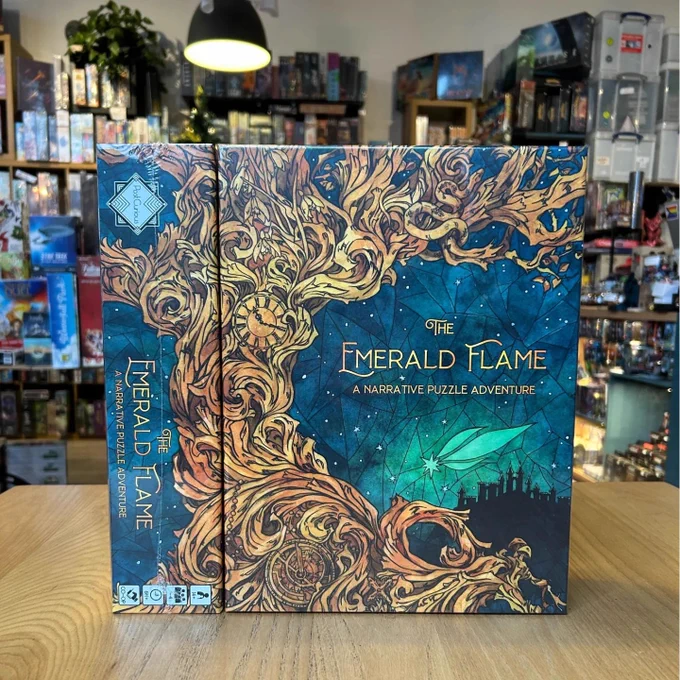 Copy of the board game The Emerald Flame with an intricate illustration on the cover. The board game shelves in the board game shop Ancient Robot Games are visible in the background.