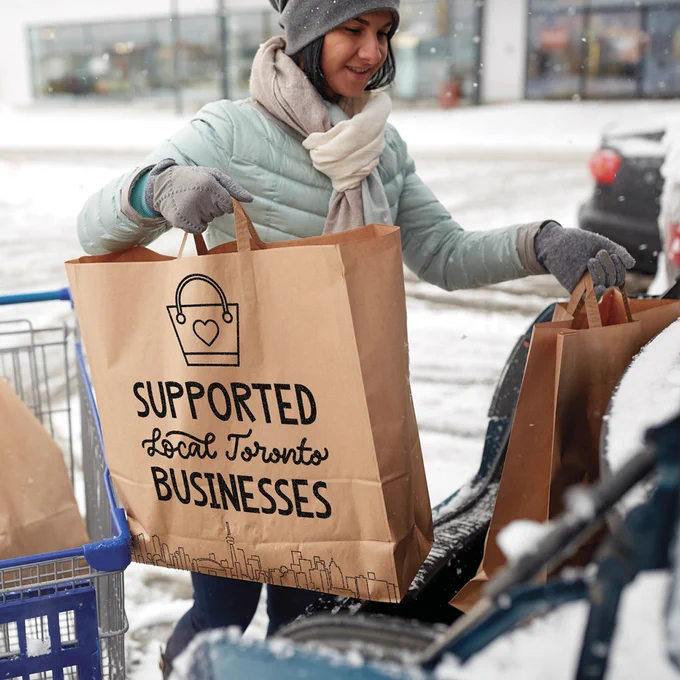 A person with a shopping bag that reads "supported local Toronto businesses'