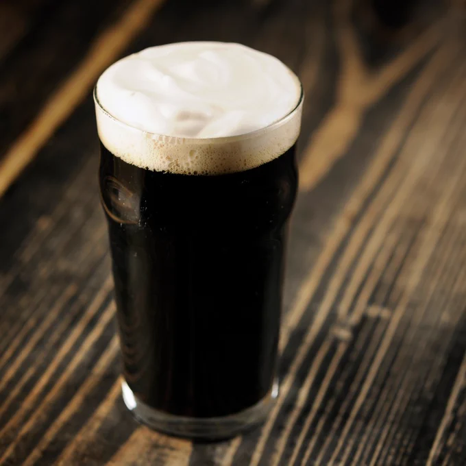 A pint of dark beer resting on the bar.