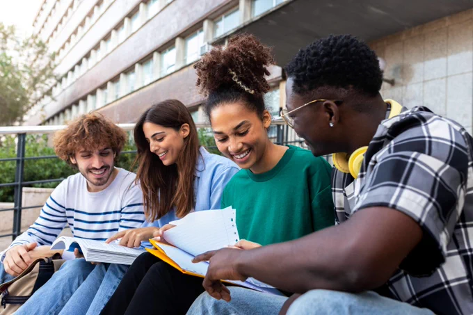 Diverse college students study together, sitting on campus steps.