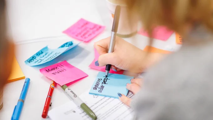 Person writing on colourful sticky paper