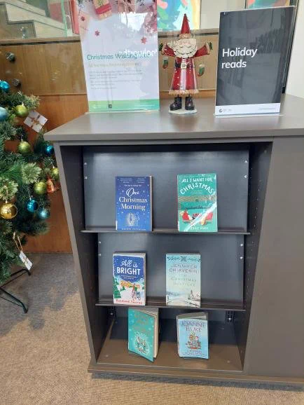 Christmas theme library book display for the holidays. Santa at the top of book shelf.