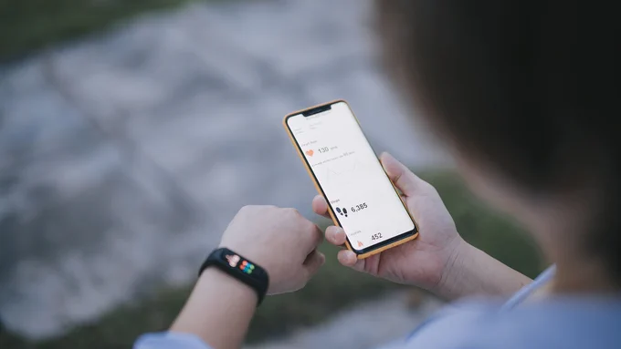 An image of a person checking health apps on a smartphone and smartwatch 