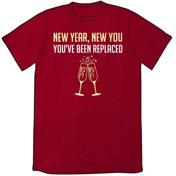 A red t-shirt with light yellow text that says "New Year, New You. You've been replaced". Below this are two champagne glasses clinking. The bubbles have a crescent moon inside them.