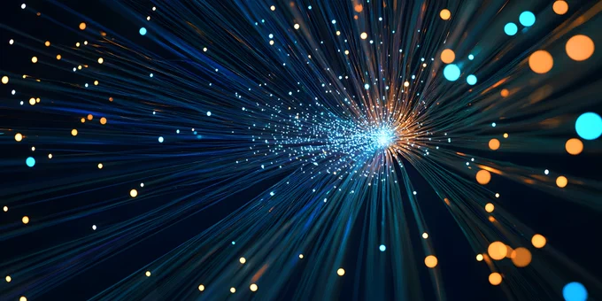 A visualisation featuring dynamic light trails and glowing particles in various shades of blue and orange, radiating outward from a central point against a dark background. 