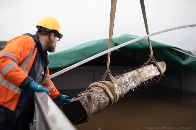 Old timbers being transferred to the large water tank by a person wearing a high-vis jacket