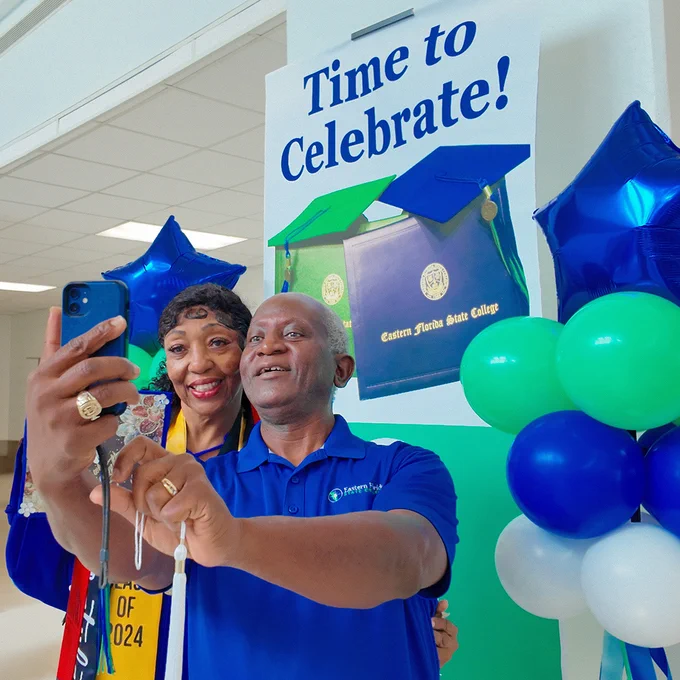 female graduate with man taking selfie image with phone