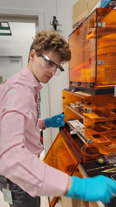 Man wearing safety goggles and gloves working at a scientific bench.