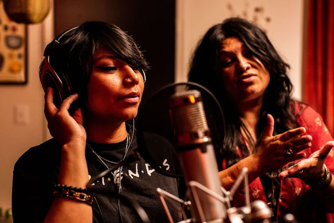 two Indigenous people recording in a radio studio