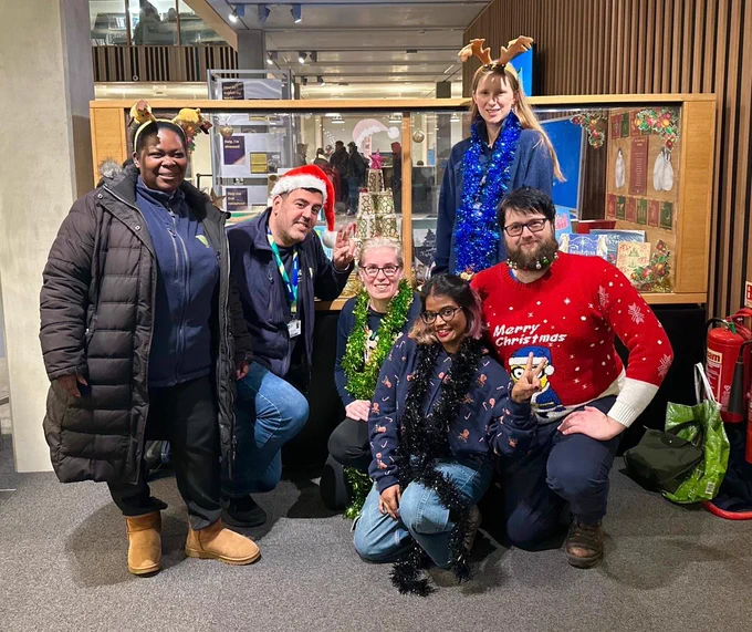 Library and Nest staff  in front of the library’s Christmas book display