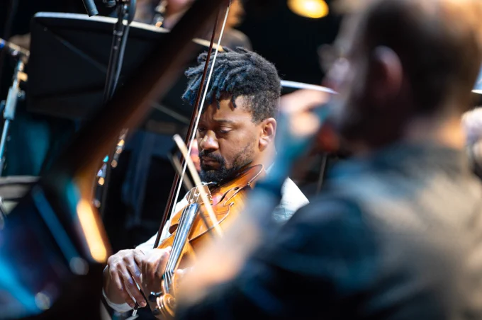 A person plays the violin in an ensemble.