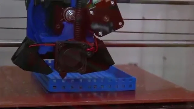 Blue and black 3-D printer sitting on a desk.