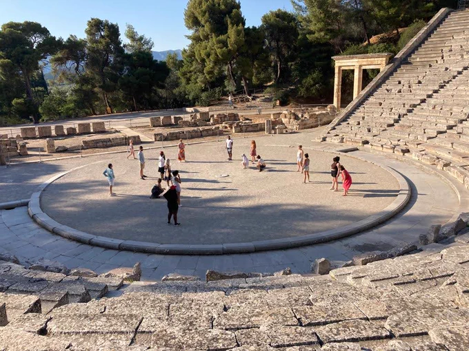 A group of students in the performance area at the ruins of Ancient Theatre of Epidaurus.