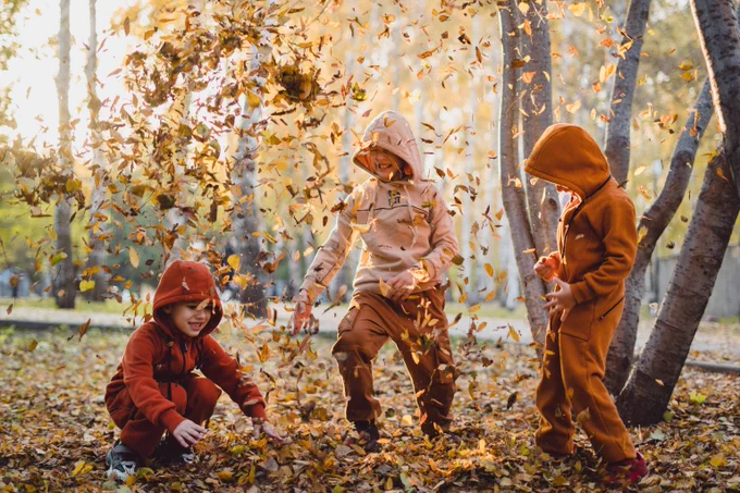 Children playing with leaves outdoors. 