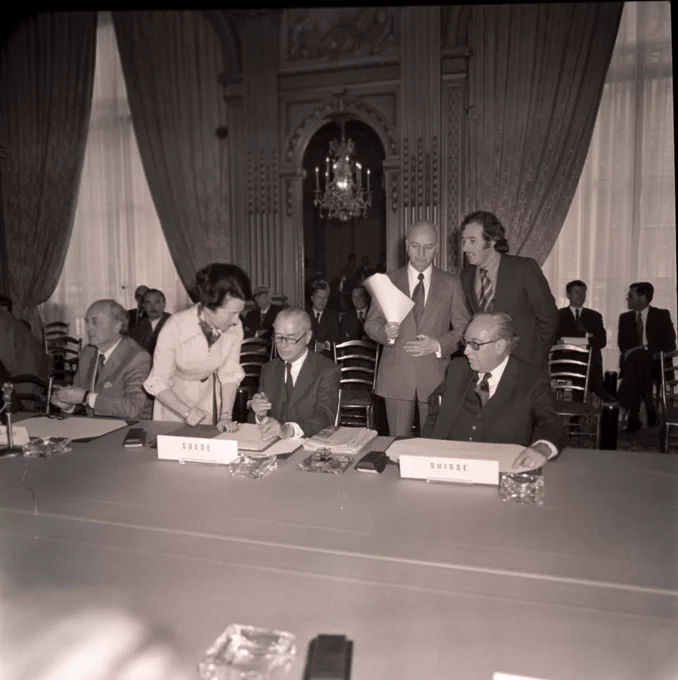 Michel Bourély standing with paper in hand at the Conference of Plenipotentiaries, 30 May 1975. With Swedish and Swiss delegates