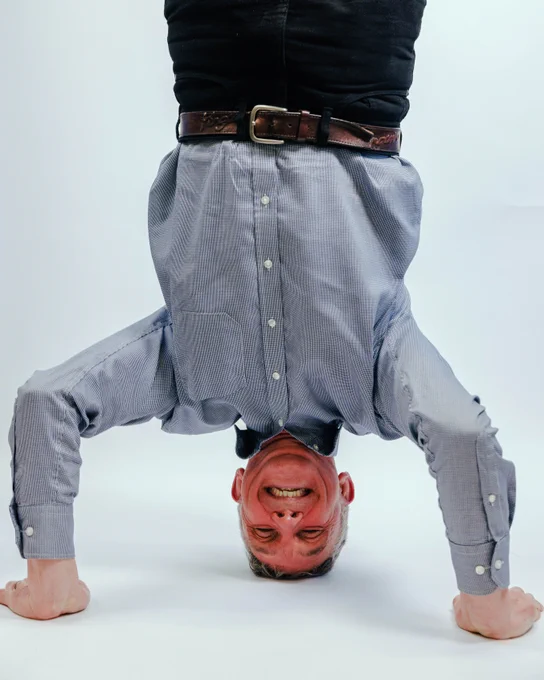 A photo of Chris Gledhill doing a headstand on a white background