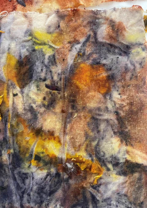A piece of fabric dyed using natural materials in shades of blue, yellow, orange and brown