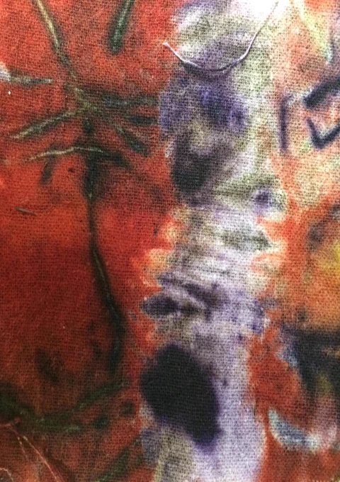 A piece of fabric dyed using natural materials in shades of red, purple, green and orange